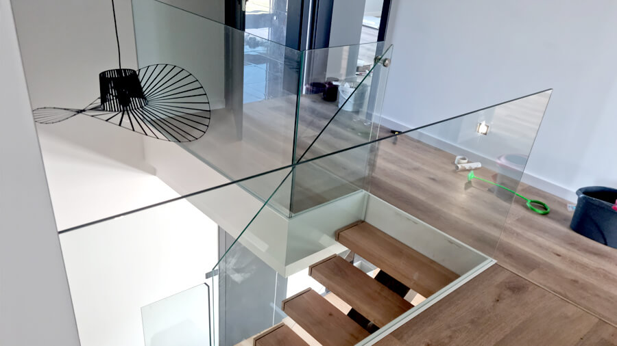 Metalowe schody wewnętrzne do domu z szklaną balustradą